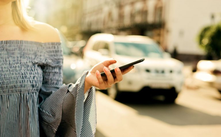 a woman using her phone to book a taxi company in Ashford